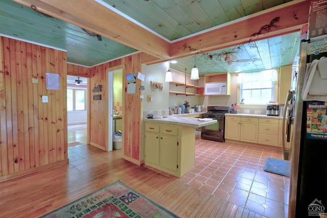 630 County Route 11, Ancram, NY 12502 - kitchen with gas stove, white microwave, tile counters, wooden walls, and freestanding refrigerator