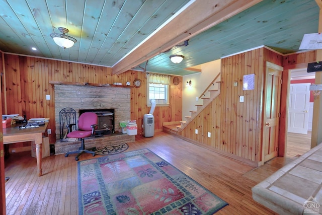630 County Route 11, Ancram, NY 12502 - living area featuring hardwood / wood-style floors, stairway, wooden walls, wood ceiling, and a wood stove
