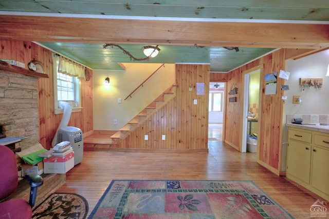 630 County Route 11, Ancram, NY 12502 - living room featuring light wood-type flooring, wooden walls, stairs, beam ceiling, and baseboards
