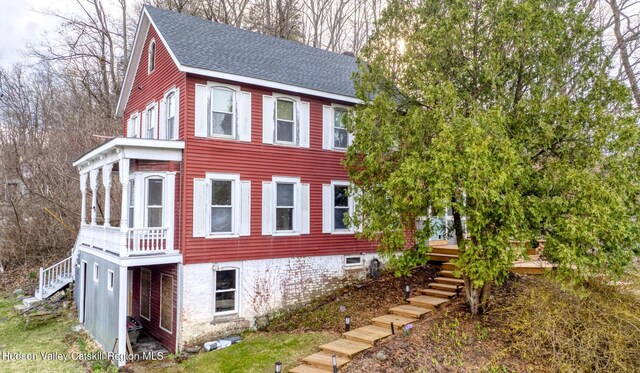 view of property exterior featuring stairs, a shingled roof, and a wooden deck