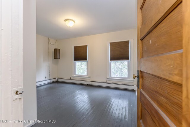 unfurnished room with dark wood-style floors and a baseboard heating unit