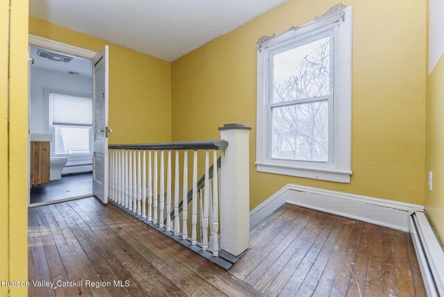 hallway with hardwood / wood-style flooring, an upstairs landing, a wealth of natural light, and a baseboard radiator