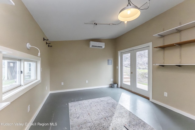 unfurnished room with a wall mounted air conditioner, concrete floors, and baseboards