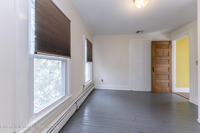 spare room with baseboards, visible vents, baseboard heating, and hardwood / wood-style floors
