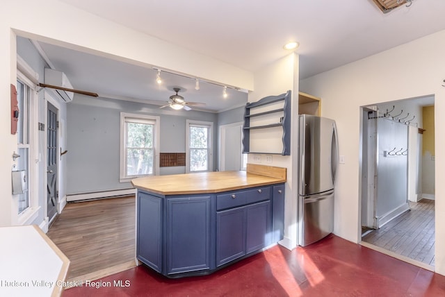 kitchen featuring a baseboard heating unit, open shelves, blue cabinets, butcher block counters, and freestanding refrigerator