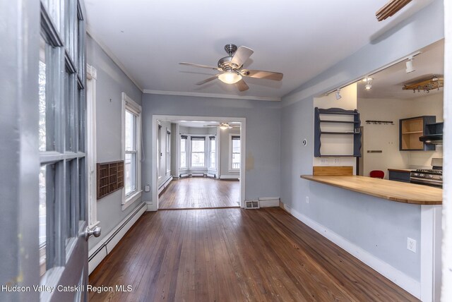 interior space featuring a baseboard radiator, rail lighting, baseboards, ceiling fan, and hardwood / wood-style floors