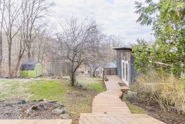 view of yard featuring an outdoor structure, a storage shed, and a deck