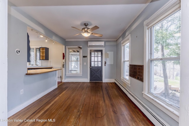 entryway with a wall mounted AC, a baseboard radiator, baseboards, hardwood / wood-style floors, and a wealth of natural light