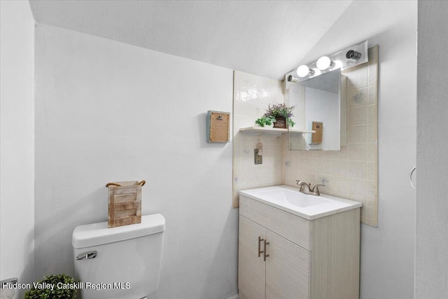bathroom featuring backsplash, toilet, vanity, and vaulted ceiling