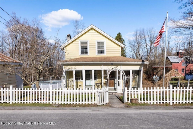 farmhouse featuring a chimney and a fenced front yard
