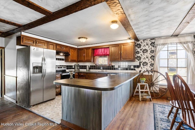 kitchen with light wood-style floors, under cabinet range hood, dark countertops, and stainless steel appliances