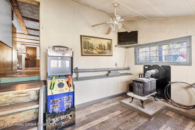 interior space with wood finished floors, ceiling fan, baseboards, and a wood stove
