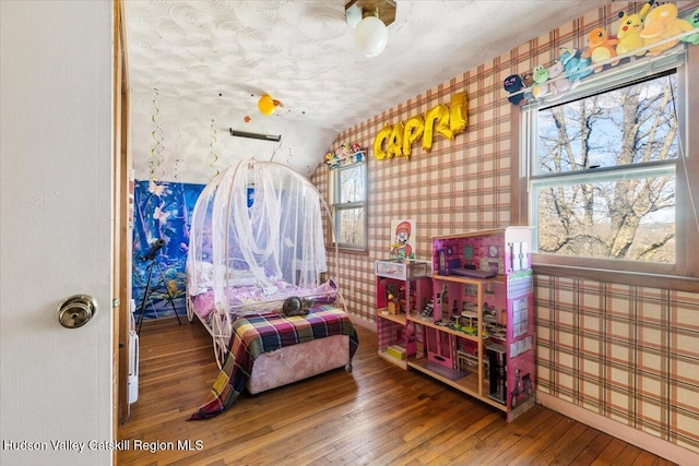 bedroom with hardwood / wood-style floors, wallpapered walls, and baseboards