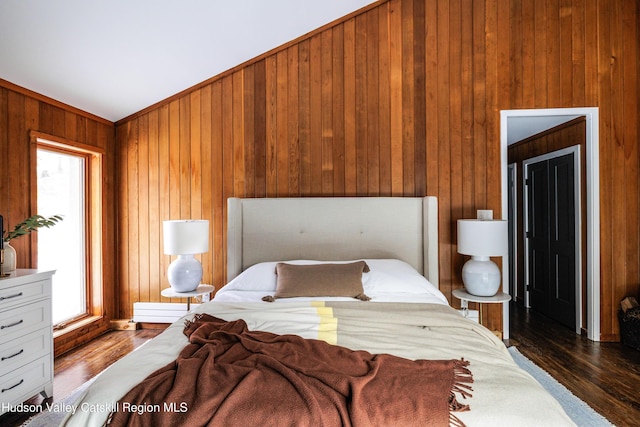 bedroom with dark hardwood / wood-style flooring and wood walls