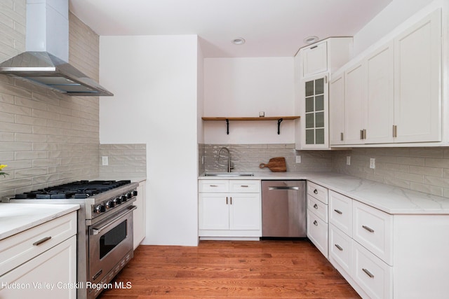 kitchen featuring white cabinetry, decorative backsplash, wall chimney range hood, sink, and stainless steel appliances