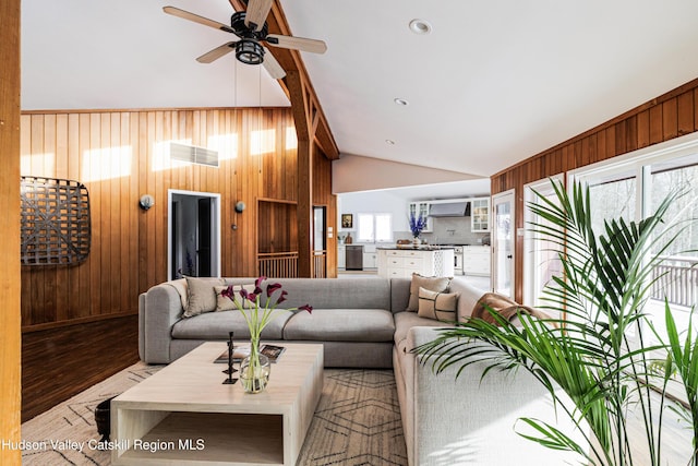 living room with wooden walls, vaulted ceiling, and a wealth of natural light