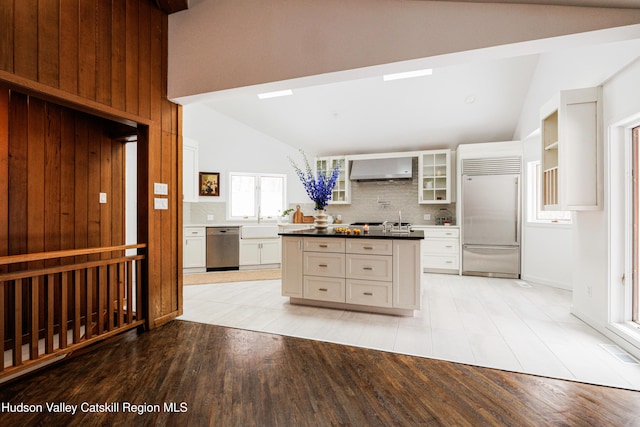 kitchen featuring decorative backsplash, white cabinets, wall chimney range hood, light wood-type flooring, and stainless steel appliances