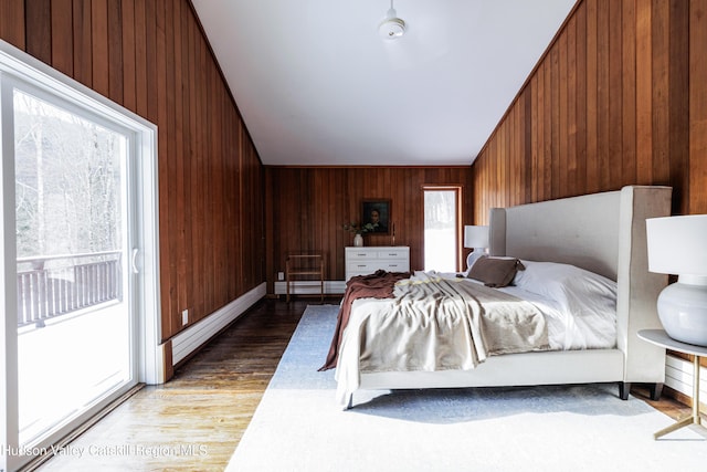 bedroom featuring wood-type flooring, wooden walls, and lofted ceiling