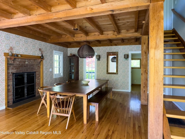 94 The Middle Way, Mount Tremper, NY 12457 - dining room featuring wallpapered walls, wooden ceiling with exposed beams, hardwood / wood-style floors, stairway, and a brick fireplace
