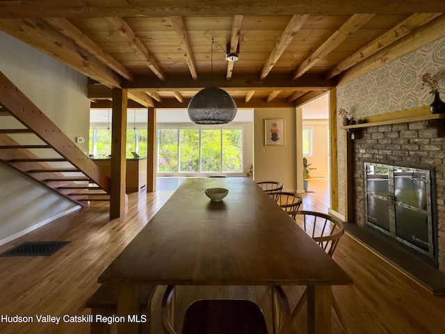 94 The Middle Way, Mount Tremper, NY 12457 - dining space with wood ceiling with exposed beams, a brick fireplace, wallpapered walls, and wood finished floors