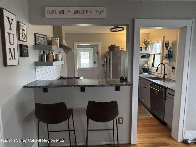 797 State Route 203, Spencertown, NY 12165 - kitchen featuring stainless steel dishwasher, a breakfast bar area, freestanding refrigerator, tasteful backsplash, and wood finished floors