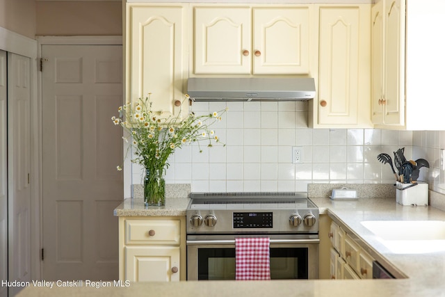 17 Stephen Dr, Hudson, NY 12534 - kitchen with stainless steel electric range, exhaust hood, backsplash, and cream cabinets