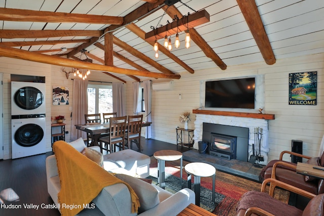 living room featuring stacked washer / drying machine, vaulted ceiling with beams, wooden walls, dark wood-type flooring, and a wood stove