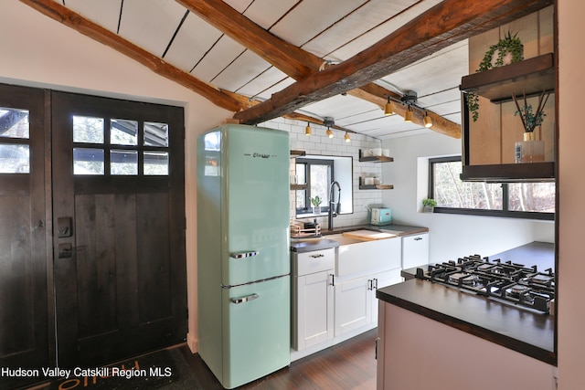 kitchen with sink, white cabinets, white fridge, and vaulted ceiling with beams