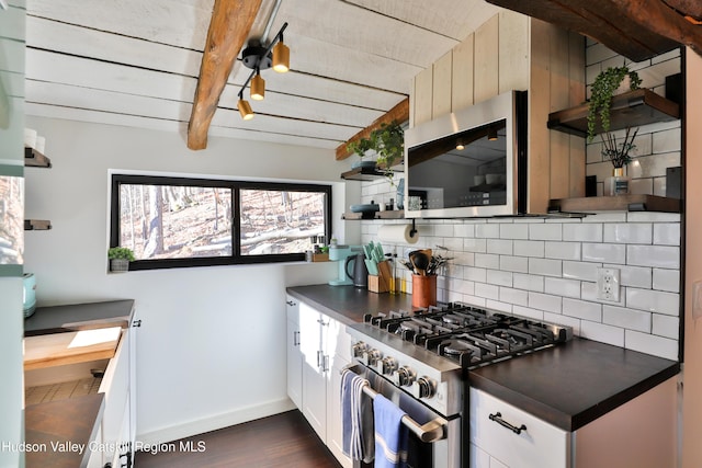 kitchen with white cabinetry, appliances with stainless steel finishes, decorative backsplash, dark hardwood / wood-style floors, and beamed ceiling