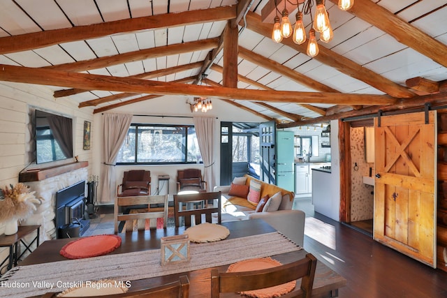 dining area featuring a barn door, dark hardwood / wood-style floors, lofted ceiling with beams, an inviting chandelier, and wood ceiling