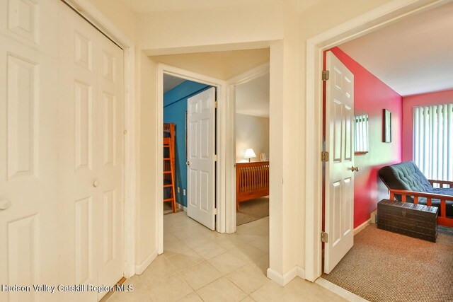 corridor with baseboards and light tile patterned flooring