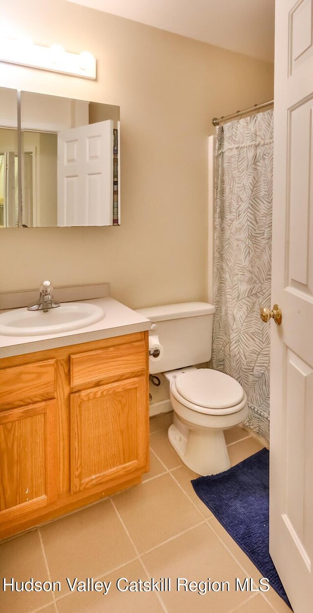 bathroom featuring tile patterned flooring, toilet, vanity, and a shower with curtain