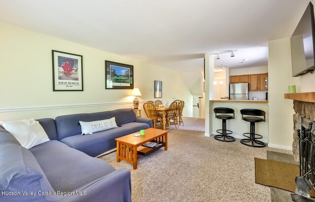 carpeted living area featuring a stone fireplace