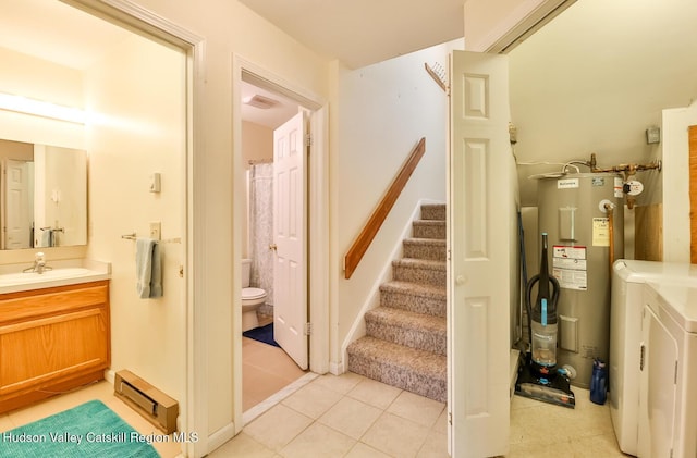 stairway featuring electric water heater, baseboard heating, independent washer and dryer, and tile patterned floors