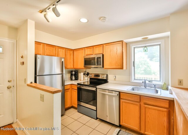 kitchen with appliances with stainless steel finishes, a sink, light countertops, and light tile patterned flooring