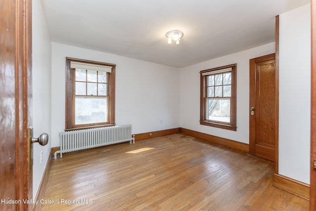 spare room with light wood-style flooring, radiator heating unit, and baseboards