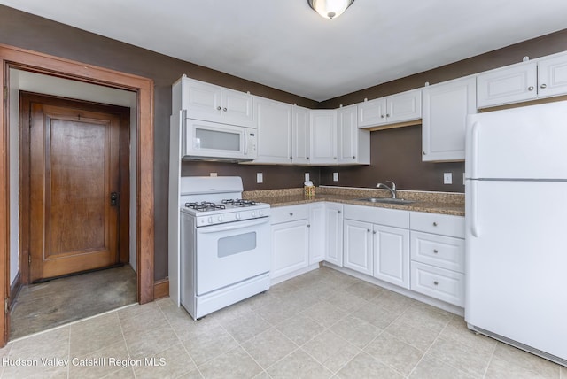 kitchen with a sink, white appliances, and white cabinets