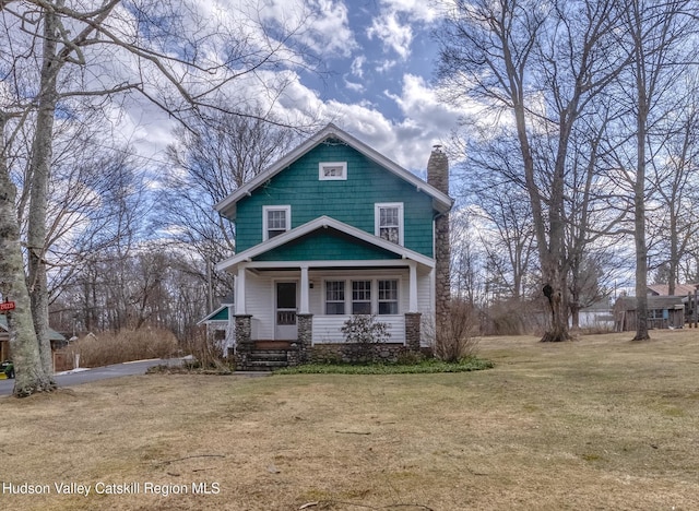 american foursquare style home with a front lawn, a porch, and a chimney