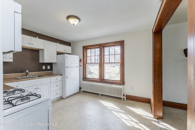 kitchen with white appliances, white cabinets, radiator heating unit, and a sink