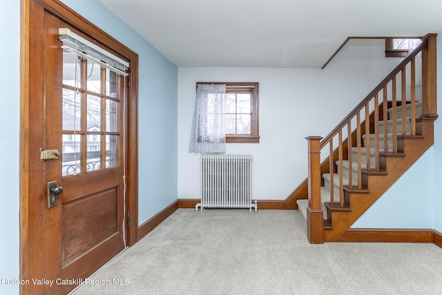 carpeted entryway with baseboards, radiator, and stairs