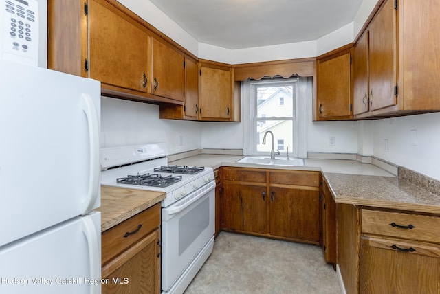 kitchen with white appliances, brown cabinetry, light countertops, and a sink