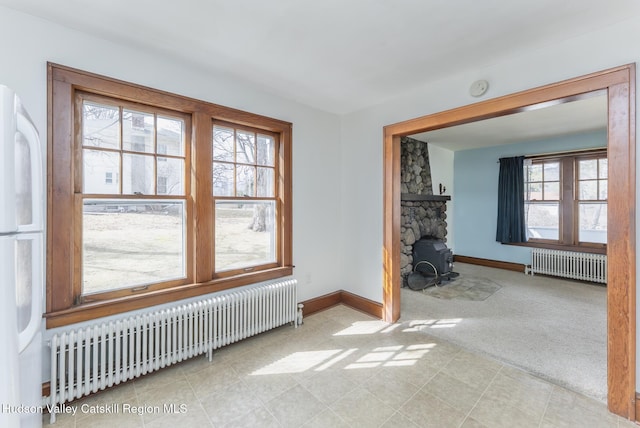 carpeted spare room with baseboards and radiator heating unit