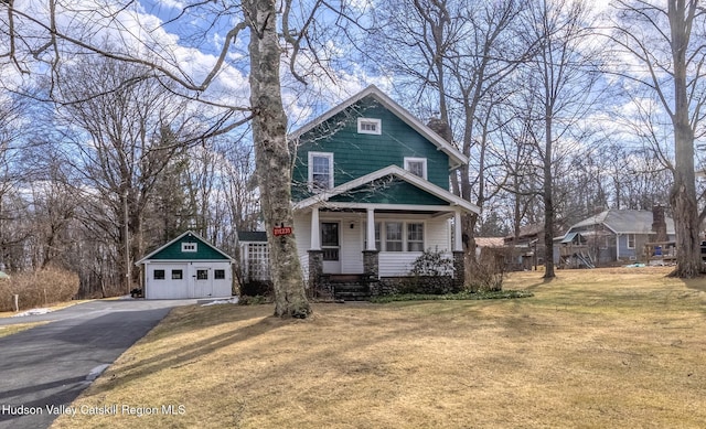 view of front facade featuring a garage, an outbuilding, a porch, and a front lawn