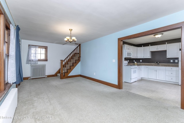 unfurnished living room with light carpet, a sink, radiator heating unit, stairway, and a chandelier