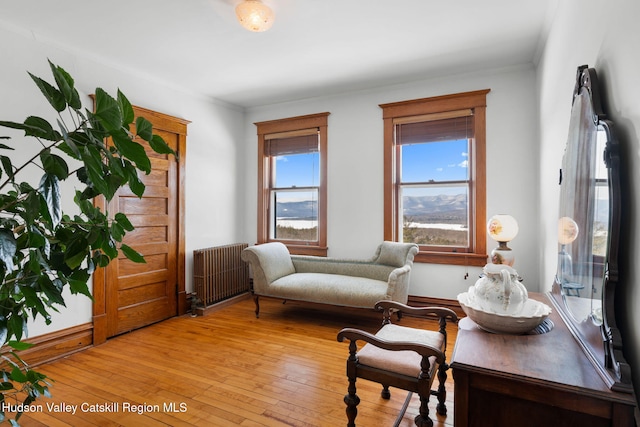 sitting room with radiator, light wood finished floors, and crown molding