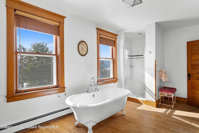 bathroom featuring a healthy amount of sunlight, a baseboard radiator, a freestanding bath, and wood finished floors