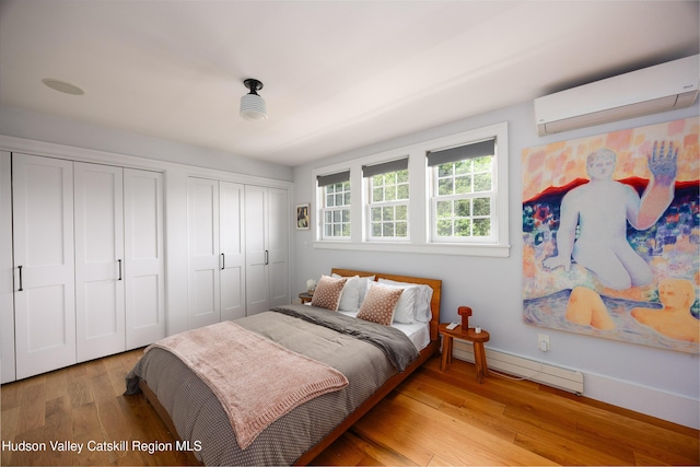 64 Dug Rd, Accord, NY 12404 - bedroom featuring a wall mounted air conditioner, multiple closets, baseboard heating, and light wood-type flooring