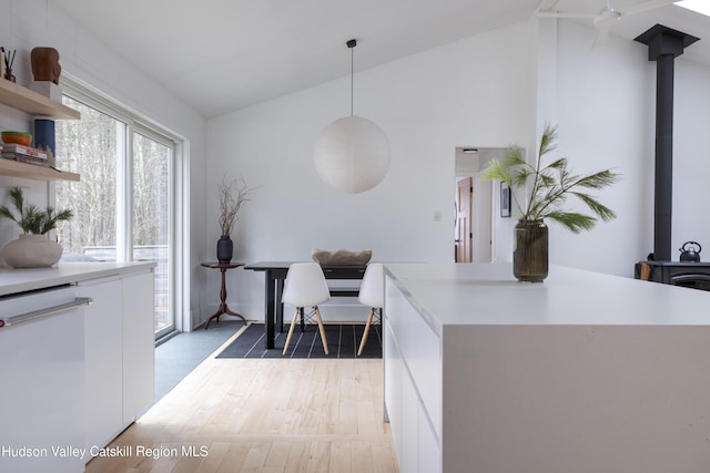 office space featuring wood-type flooring, a wood stove, and vaulted ceiling