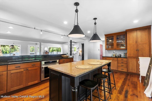 162 Methodist Farm Rd, Averill Park, NY 12018 - kitchen with oven, black electric stovetop, brown cabinetry, a center island, and glass insert cabinets