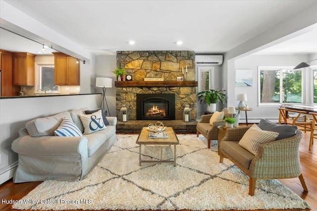 162 Methodist Farm Rd, Averill Park, NY 12018 - living room with a wall mounted AC, wood finished floors, a stone fireplace, recessed lighting, and baseboard heating
